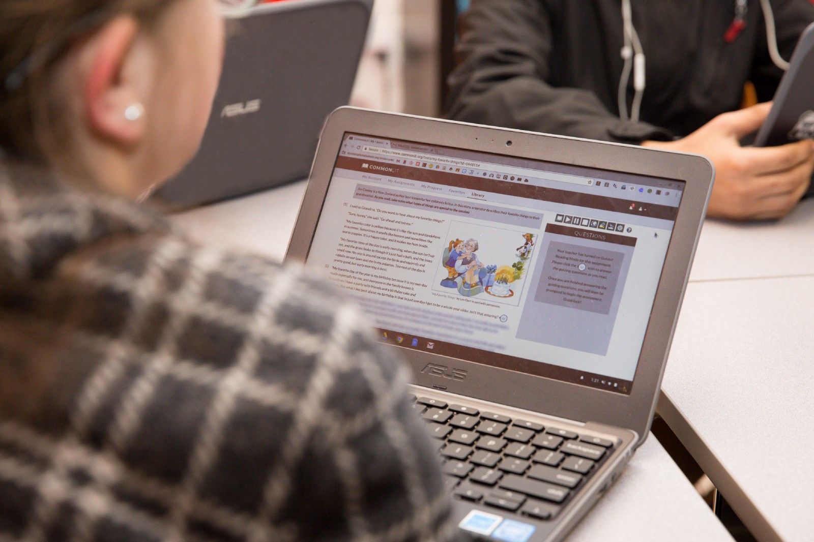 A student sitting at a table and working on a CommonLit lesson. 