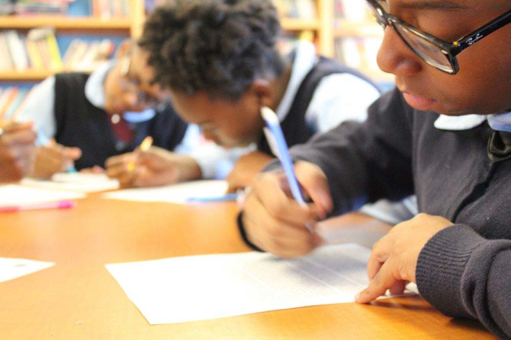 Students working on their assignments together on a desk.