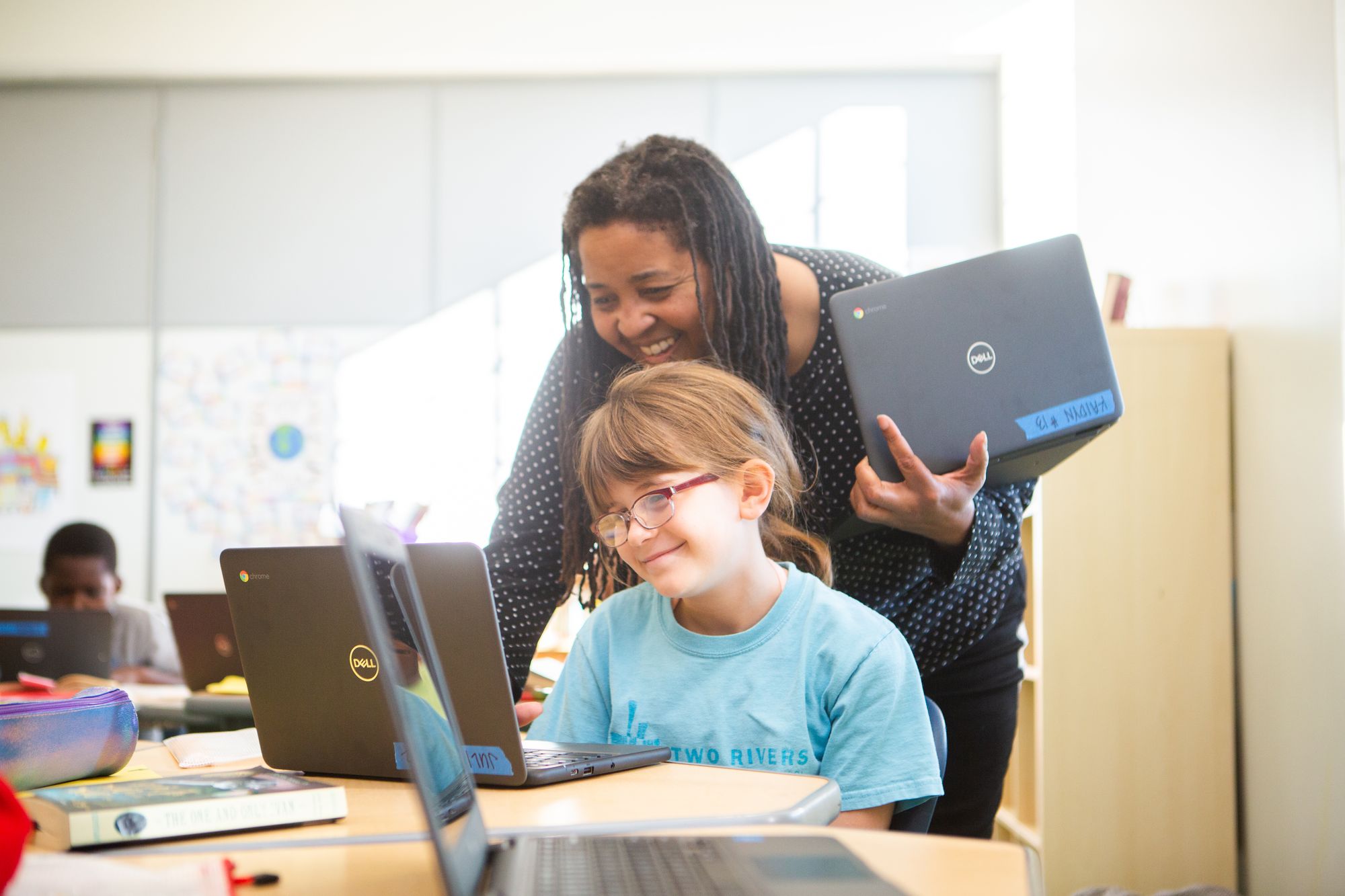 A teacher helps a young student with a CommonLit lesson. 