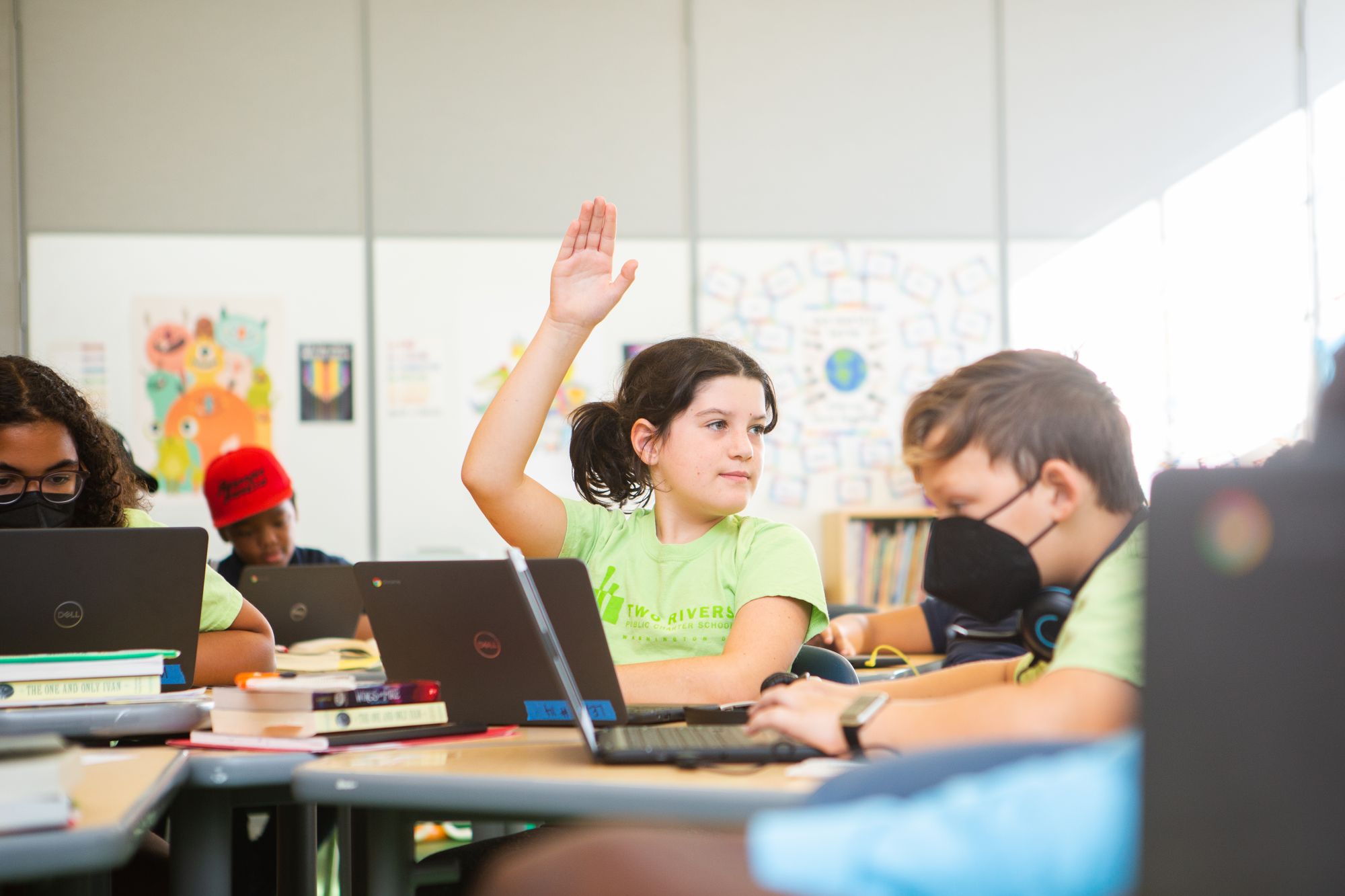 A elementary-aged student raises hand to ask a question about a Target Lesson during class.