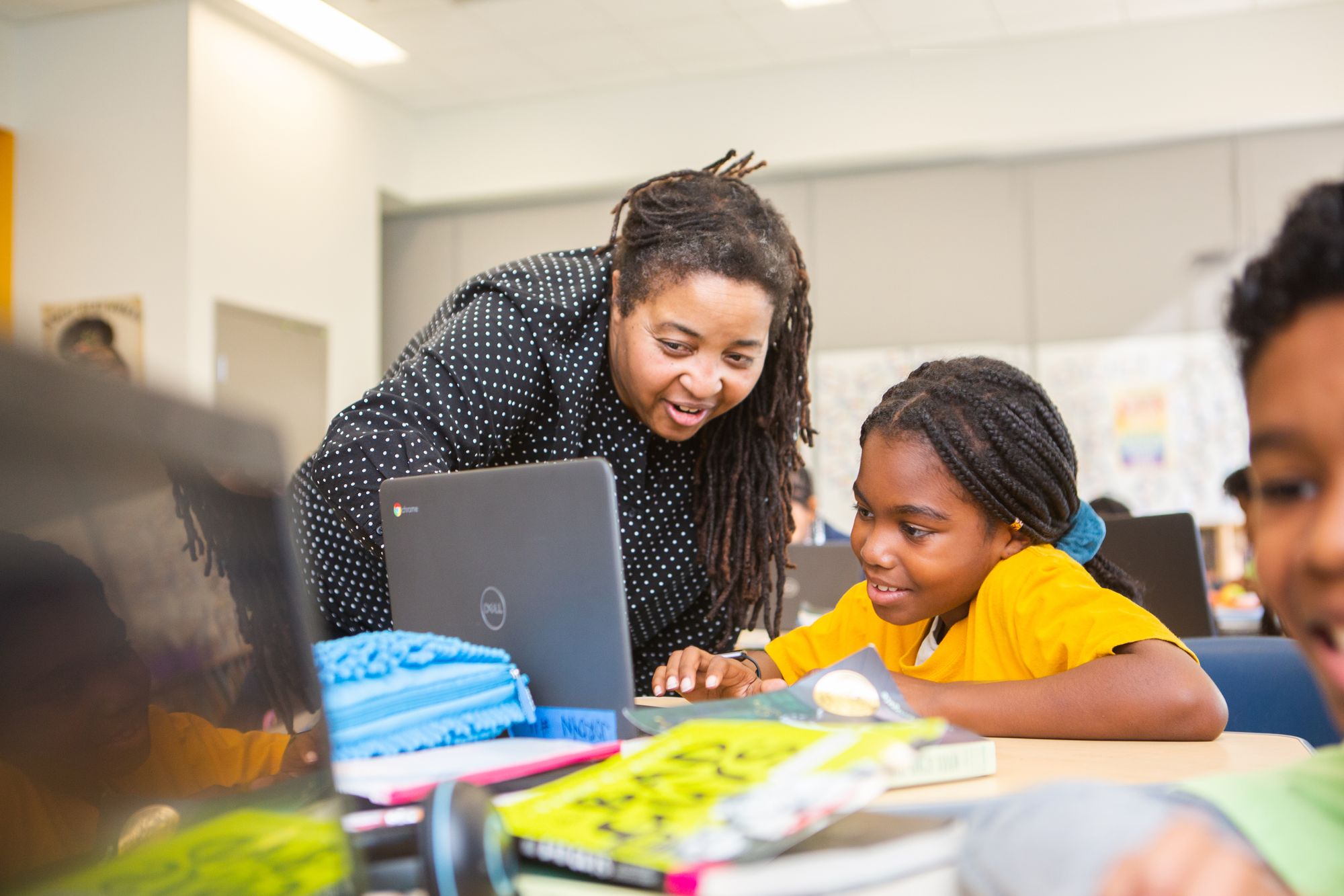 Smiling teacher and student reviewing school work on a laptop computer