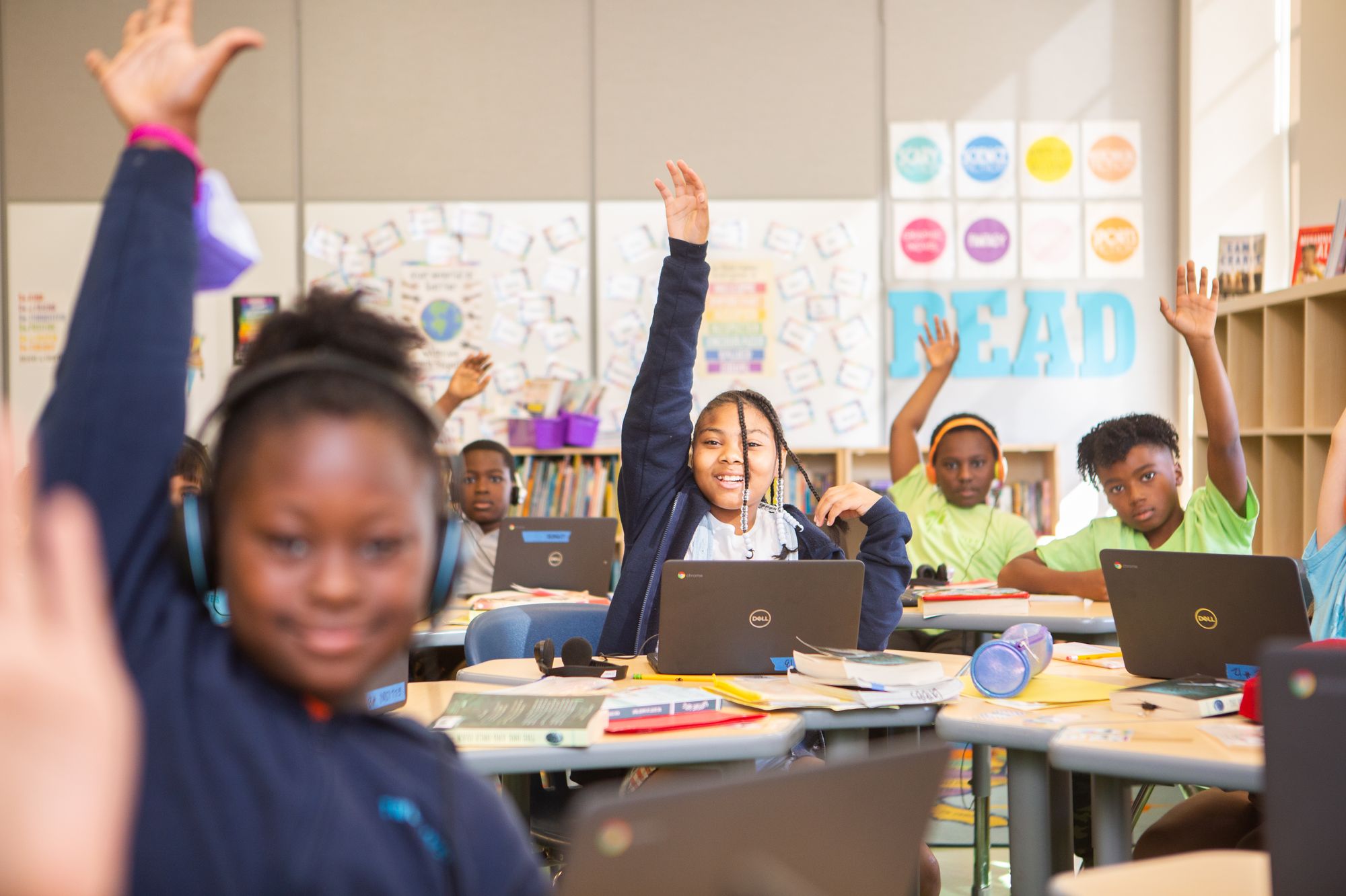 Smiling students raising their hands in a classroom