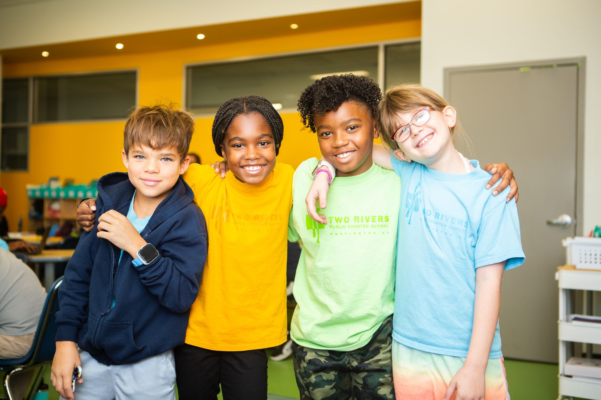 Four elementary school students smile and pose together. 