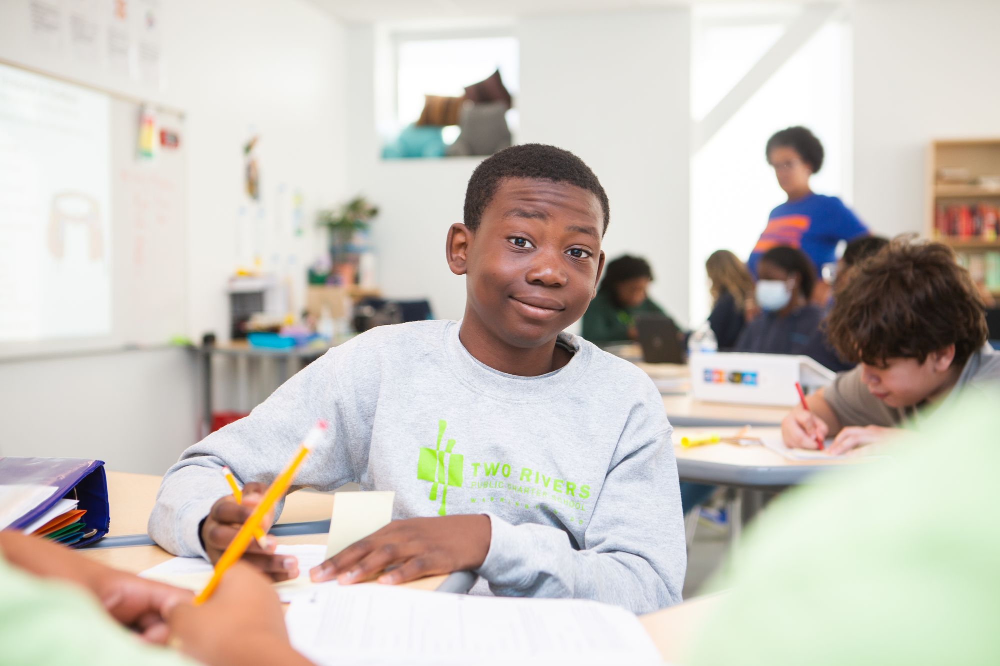 Student grins at camera, looking up from reading lesson. 