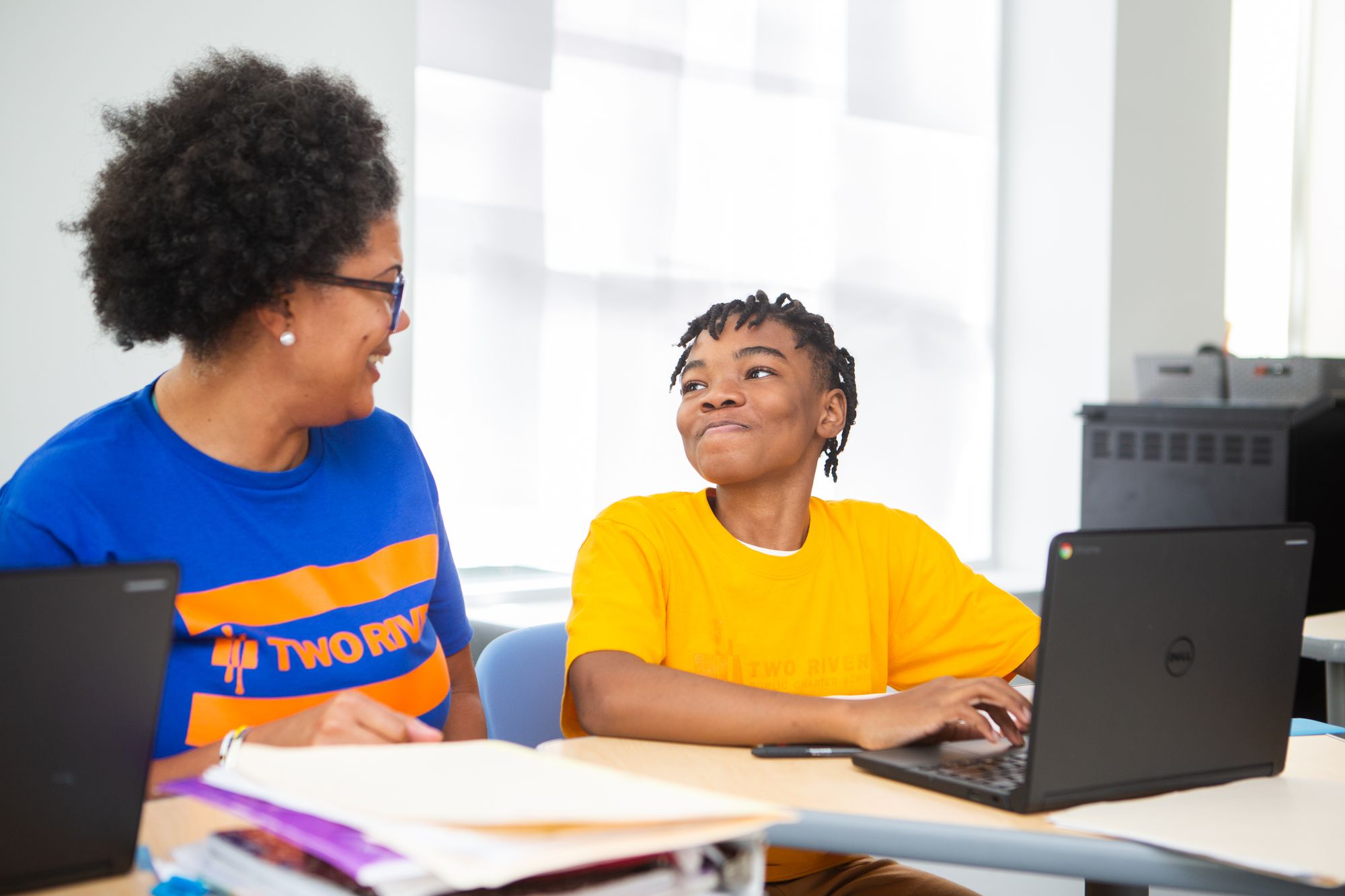 Student on a laptop smiling proudly at his teacher as he is learning.