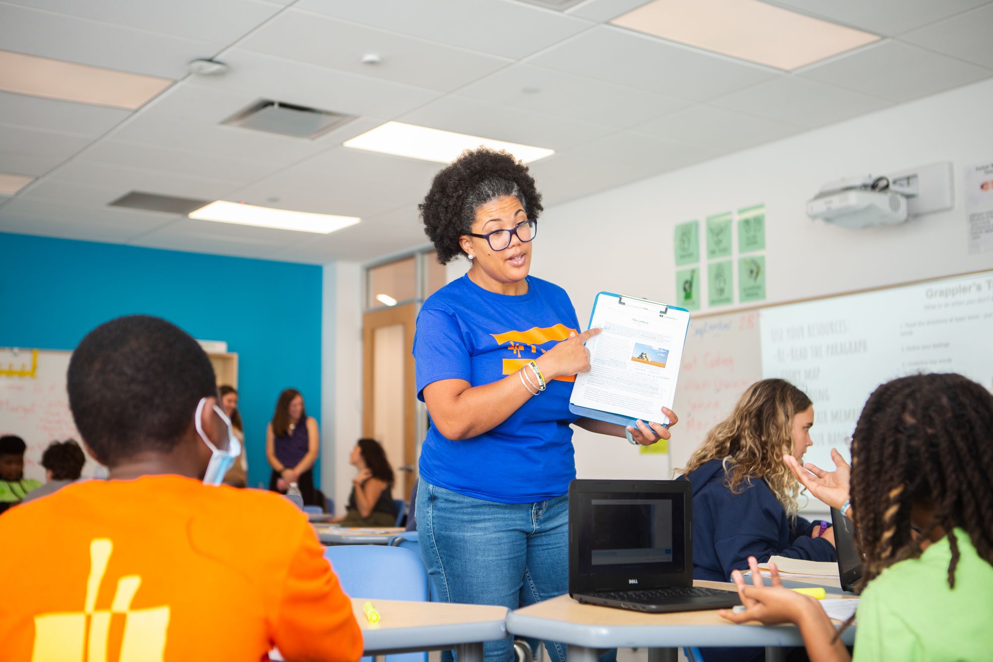 A teacher holding up a clipboard for her students