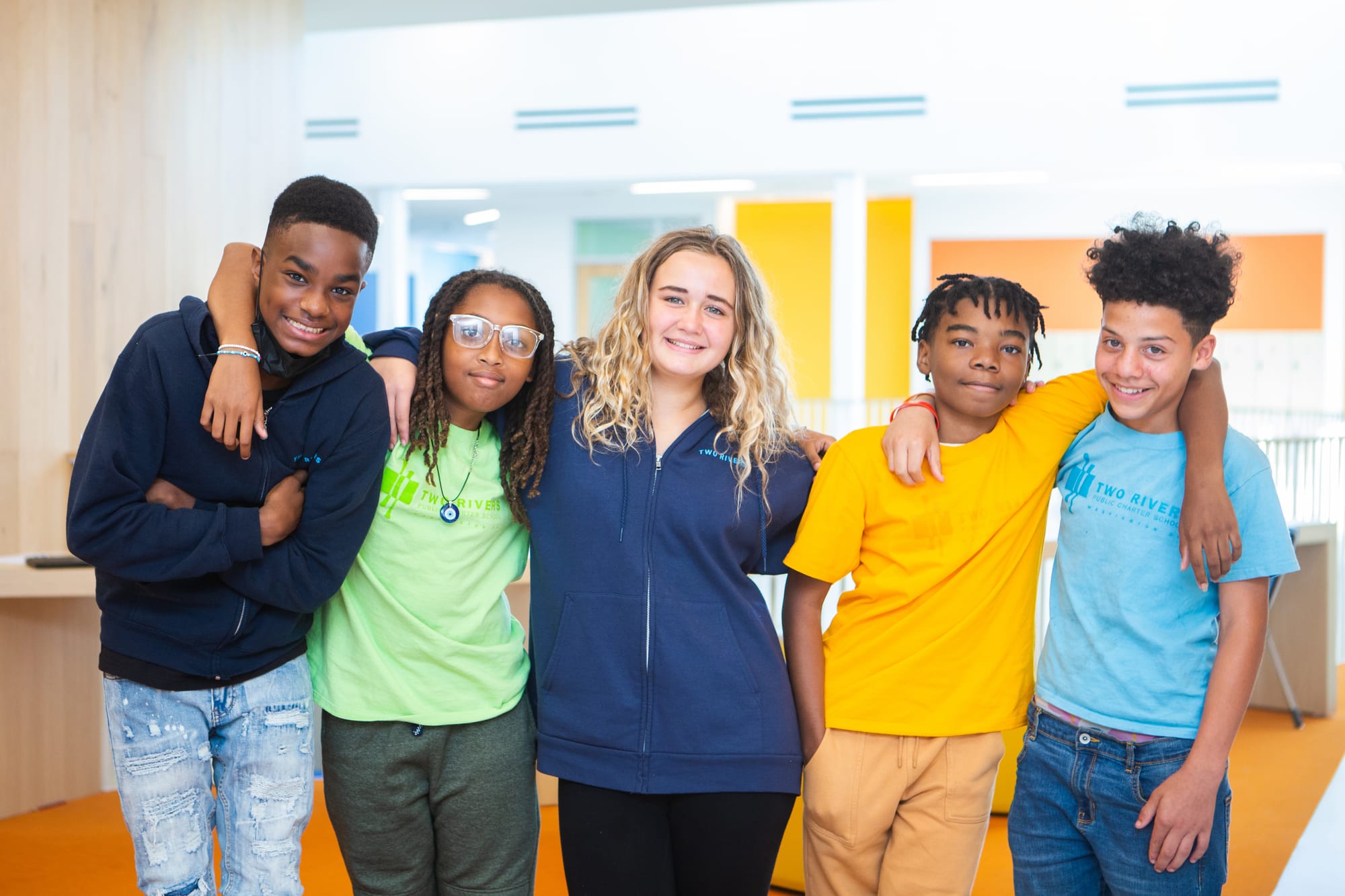 Students standing arm in arm and smiling.