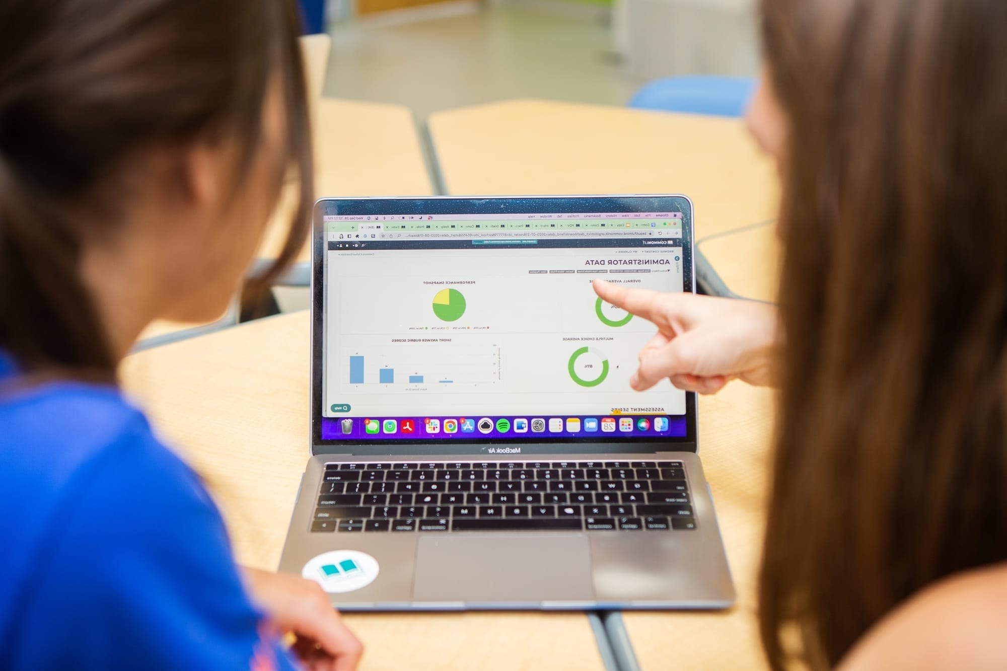 Teacher pointing out data on a computer screen to another teacher